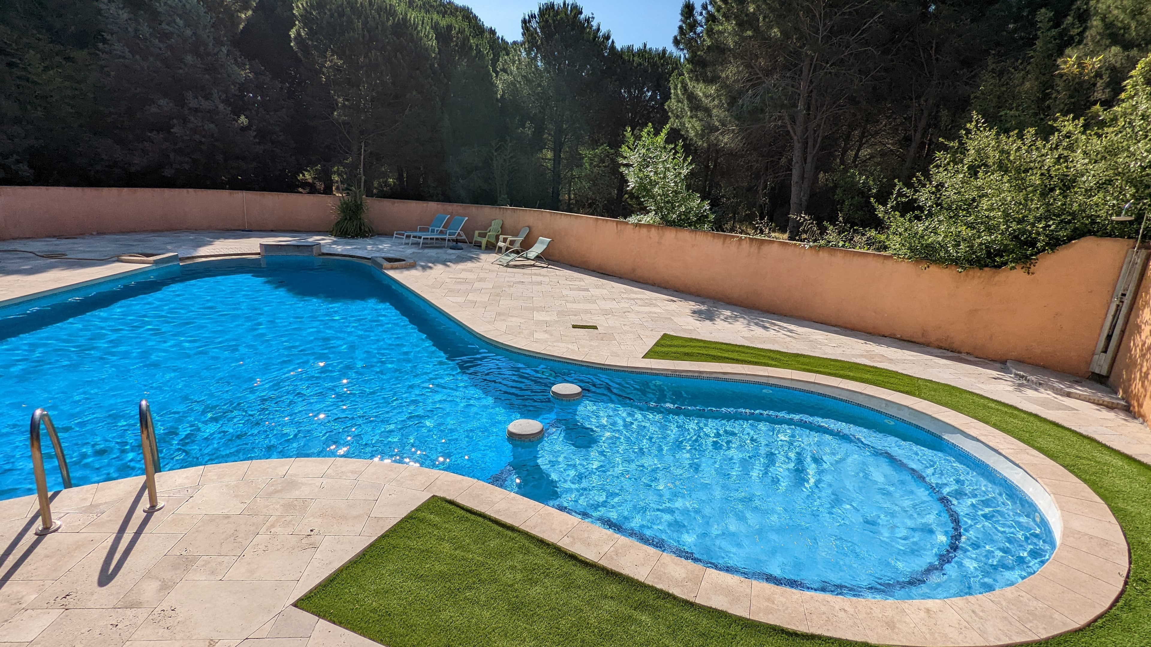 Piscine commune chauffée du domaine Allocigale, bordée de pins et de pelouse